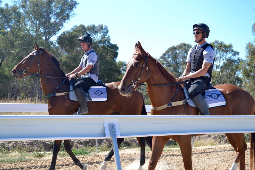 2 jockeys riding racehorses.